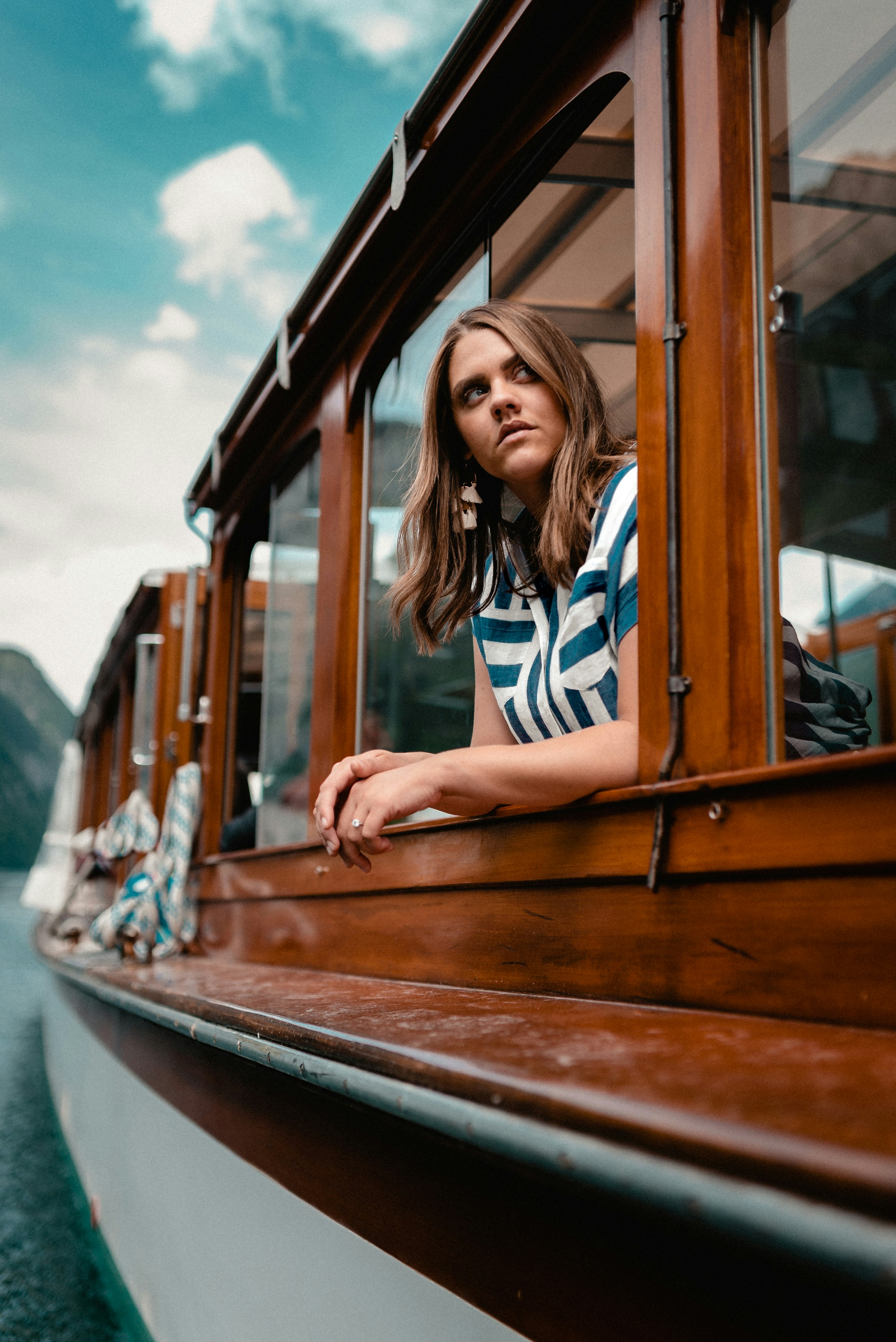 woman in blue and white striped shirt sitting on brown wooden vehicle